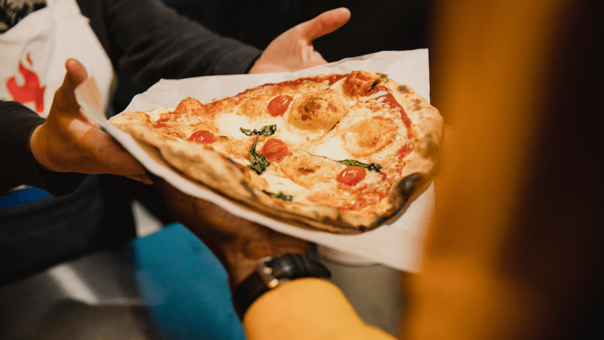 Wood-fired margherita pizza slice served fresh from a Food Truck League pizza truck