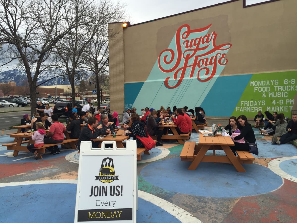 Residents sitted and eating on benches after being served at a recurring food truck event