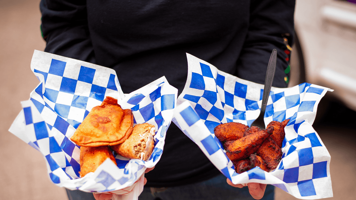 Hands holding two food truck baskets of empanadas and fried plantains, part of building team culture through office lunch ideas