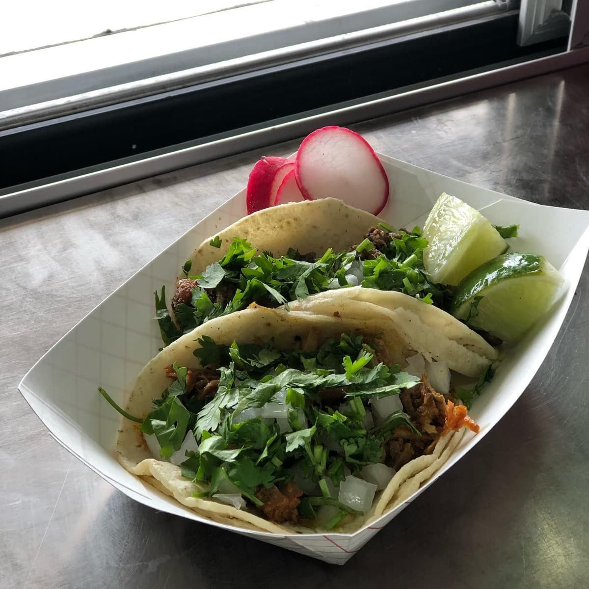Street tacos with cilantro, white onion, radish and lime served from a food truck catering setup