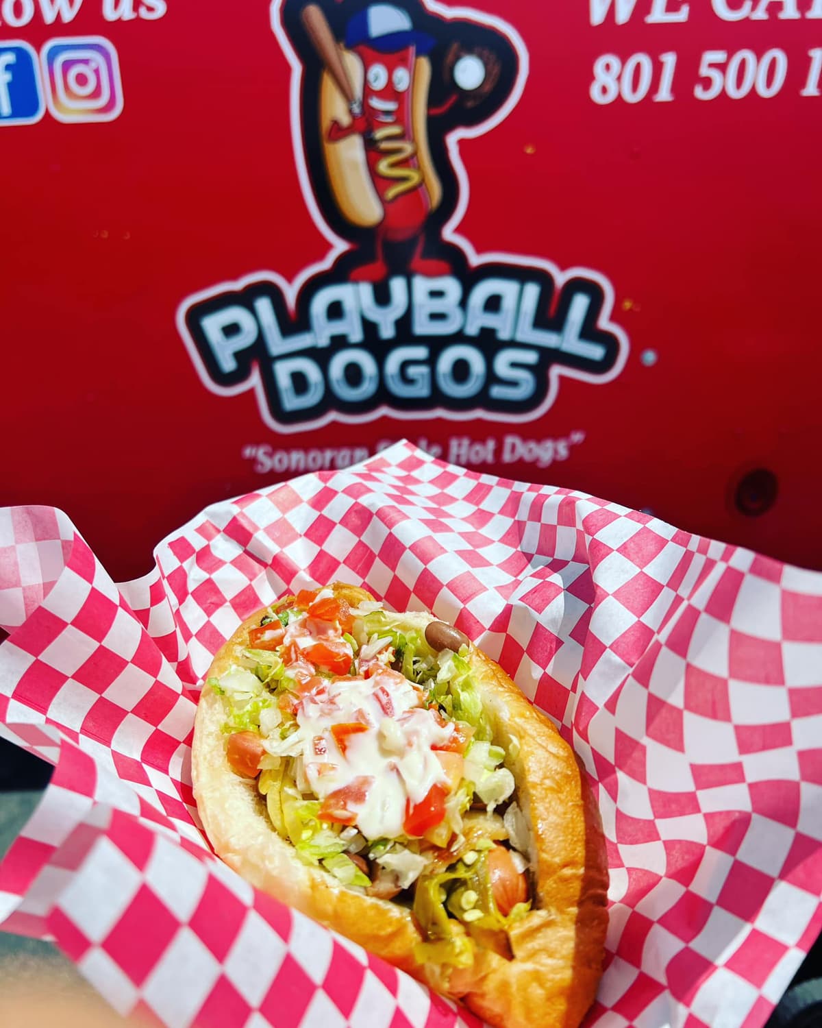 Sonoran-style hot dog topped with pico de gallo and creamy sauce from a food truck
